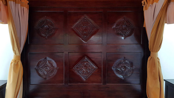 dark brown teak bed frame with carvings